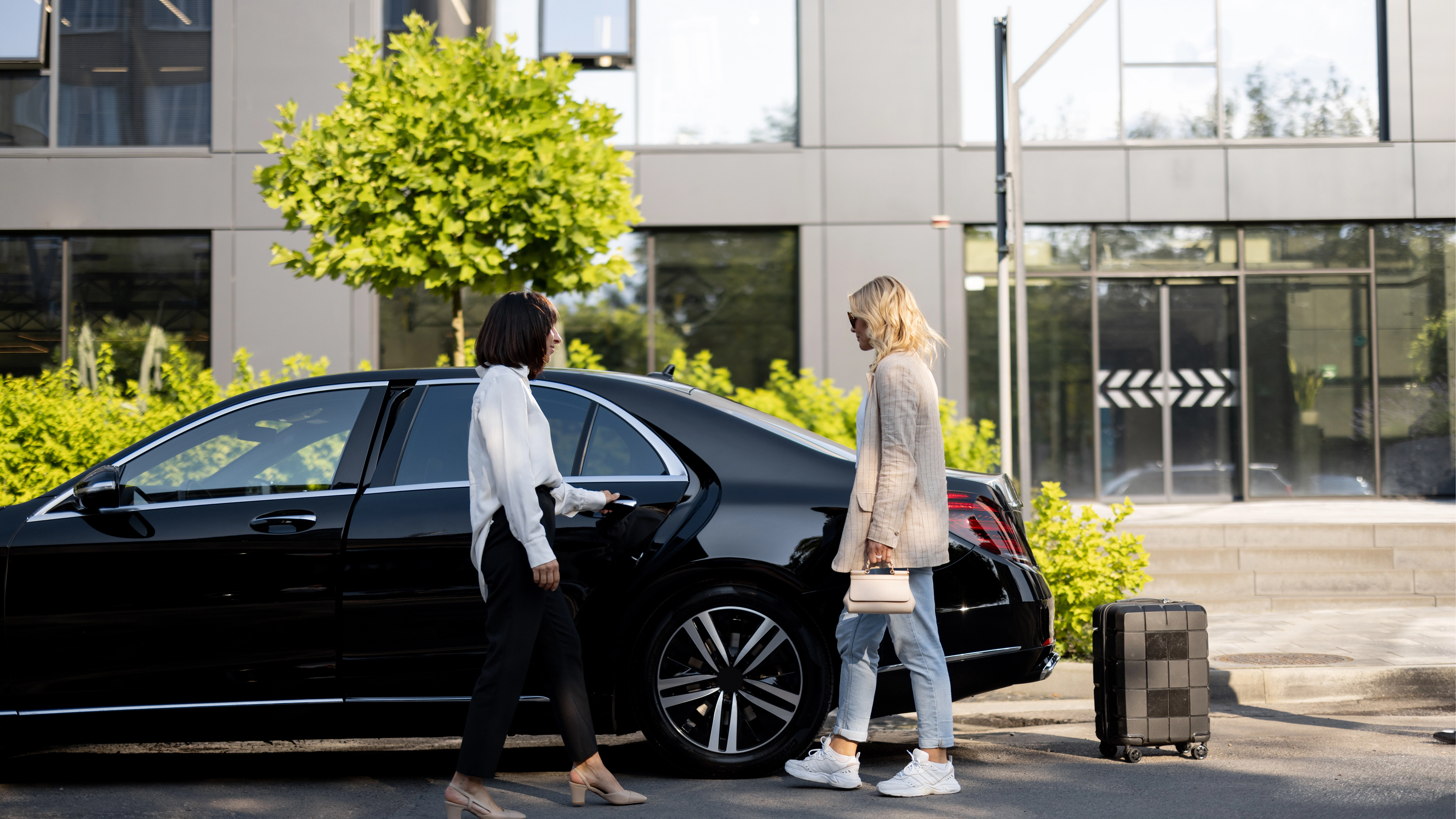 Professional travelers with luxury black sedan and luggage