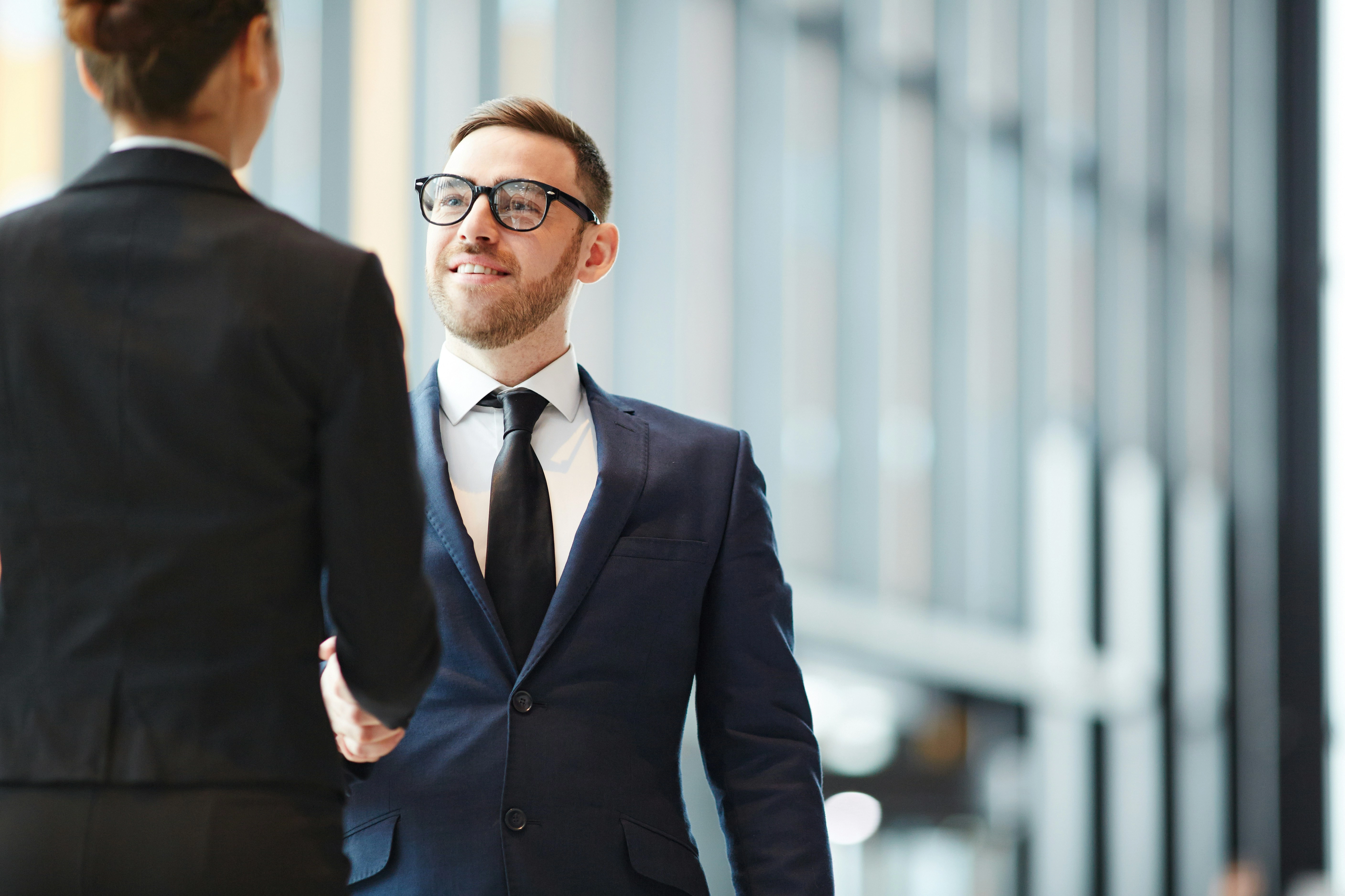 Professional chauffeur greeting passenger with warm handshake at airport